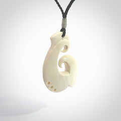 Hand carved bone hook pendant hand made by Peter Mitchell in New Zealand. This bone hook is provided with an adjustable black cord and packaged in a woven kete pouch. Free delivery worldwide.