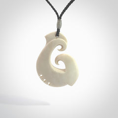 Hand carved bone hook pendant hand made by Peter Mitchell in New Zealand. This bone hook is provided with an adjustable black cord and packaged in a woven kete pouch. Free delivery worldwide.