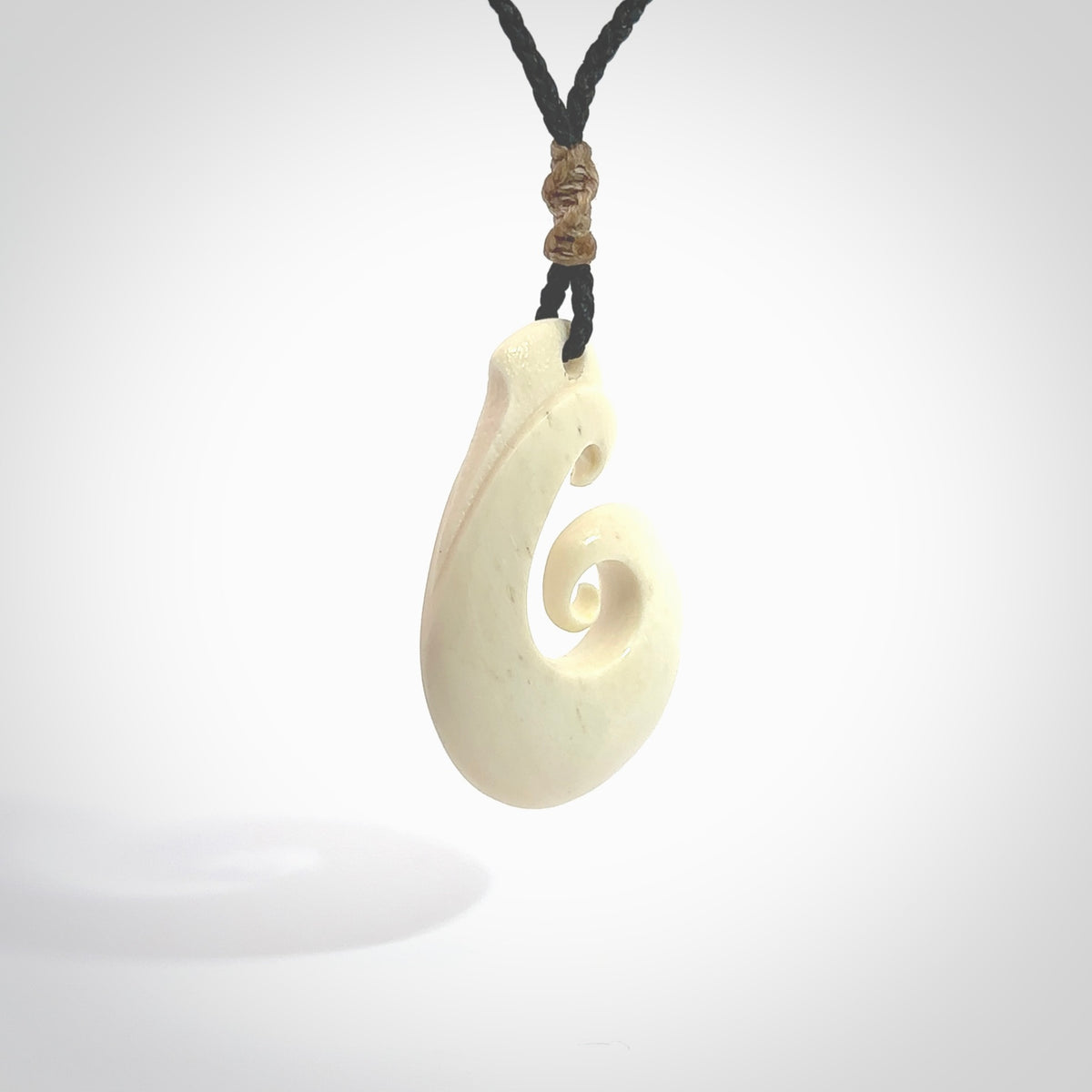 Hand carved bone hook pendant hand made by Peter Mitchell in New Zealand. This bone hook is provided with an adjustable black cord and packaged in a woven kete pouch. Free delivery worldwide.