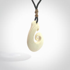 Hand carved bone hook pendant hand made by Peter Mitchell in New Zealand. This bone hook is provided with an adjustable black cord and packaged in a woven kete pouch. Free delivery worldwide.