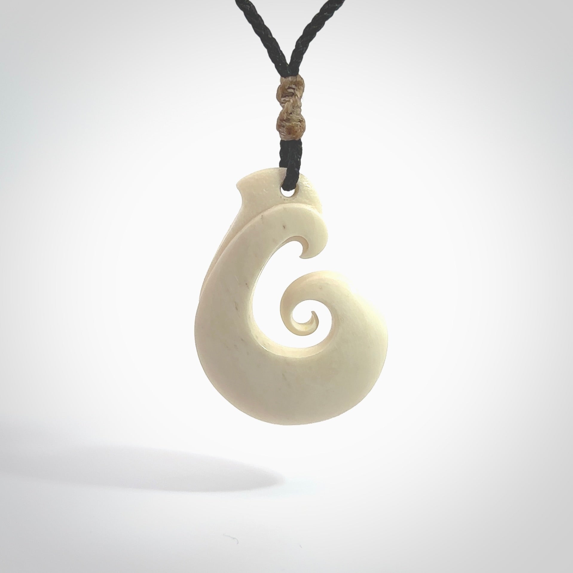 Hand carved bone hook pendant hand made by Peter Mitchell in New Zealand. This bone hook is provided with an adjustable black cord and packaged in a woven kete pouch. Free delivery worldwide.