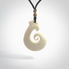 Hand carved bone hook pendant hand made by Peter Mitchell in New Zealand. This bone hook is provided with an adjustable black cord and packaged in a woven kete pouch. Free delivery worldwide.