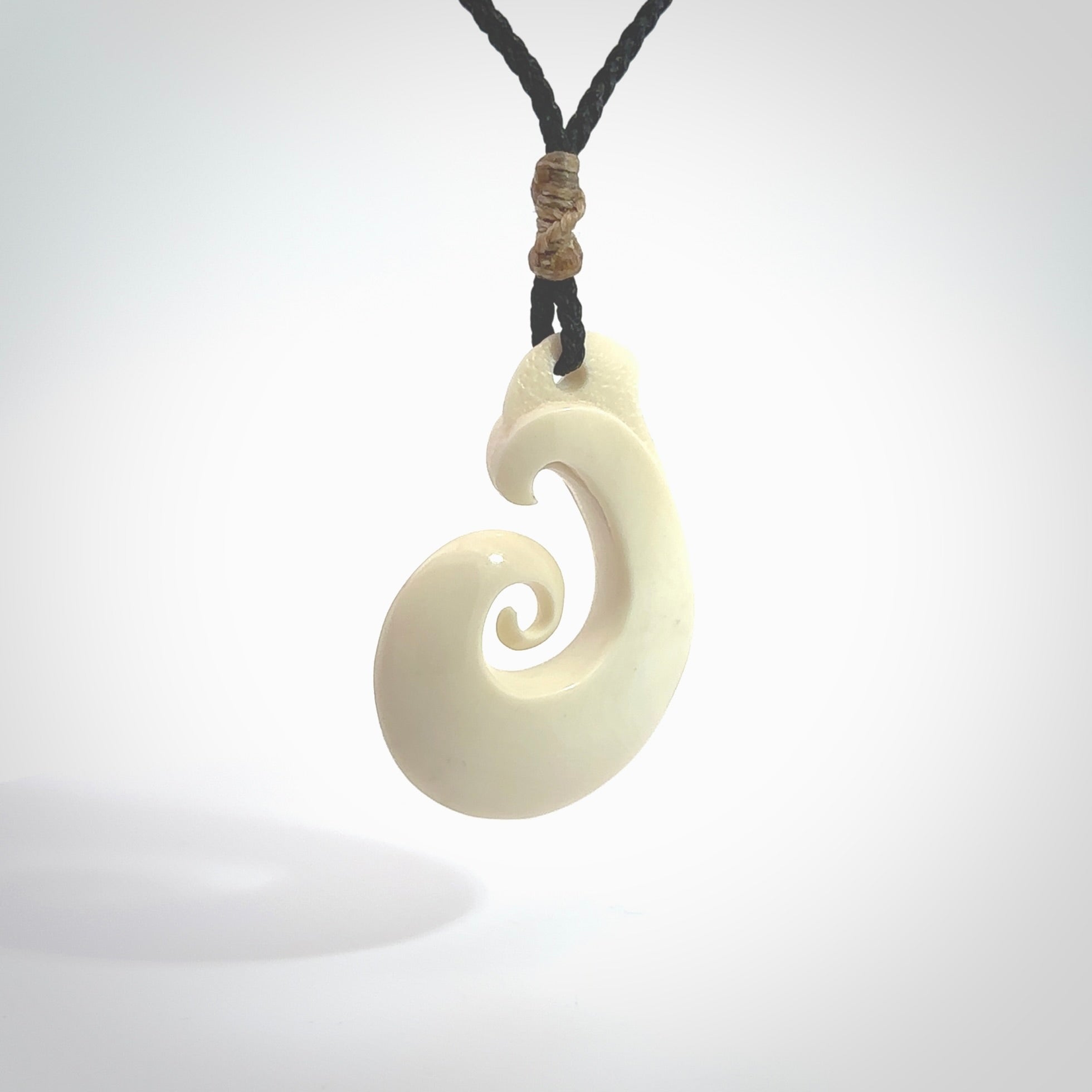 Hand carved bone hook pendant hand made by Peter Mitchell in New Zealand. This bone hook is provided with an adjustable black cord and packaged in a woven kete pouch. Free delivery worldwide.