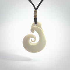 Hand carved bone hook pendant hand made by Peter Mitchell in New Zealand. This bone hook is provided with an adjustable black cord and packaged in a woven kete pouch. Free delivery worldwide.