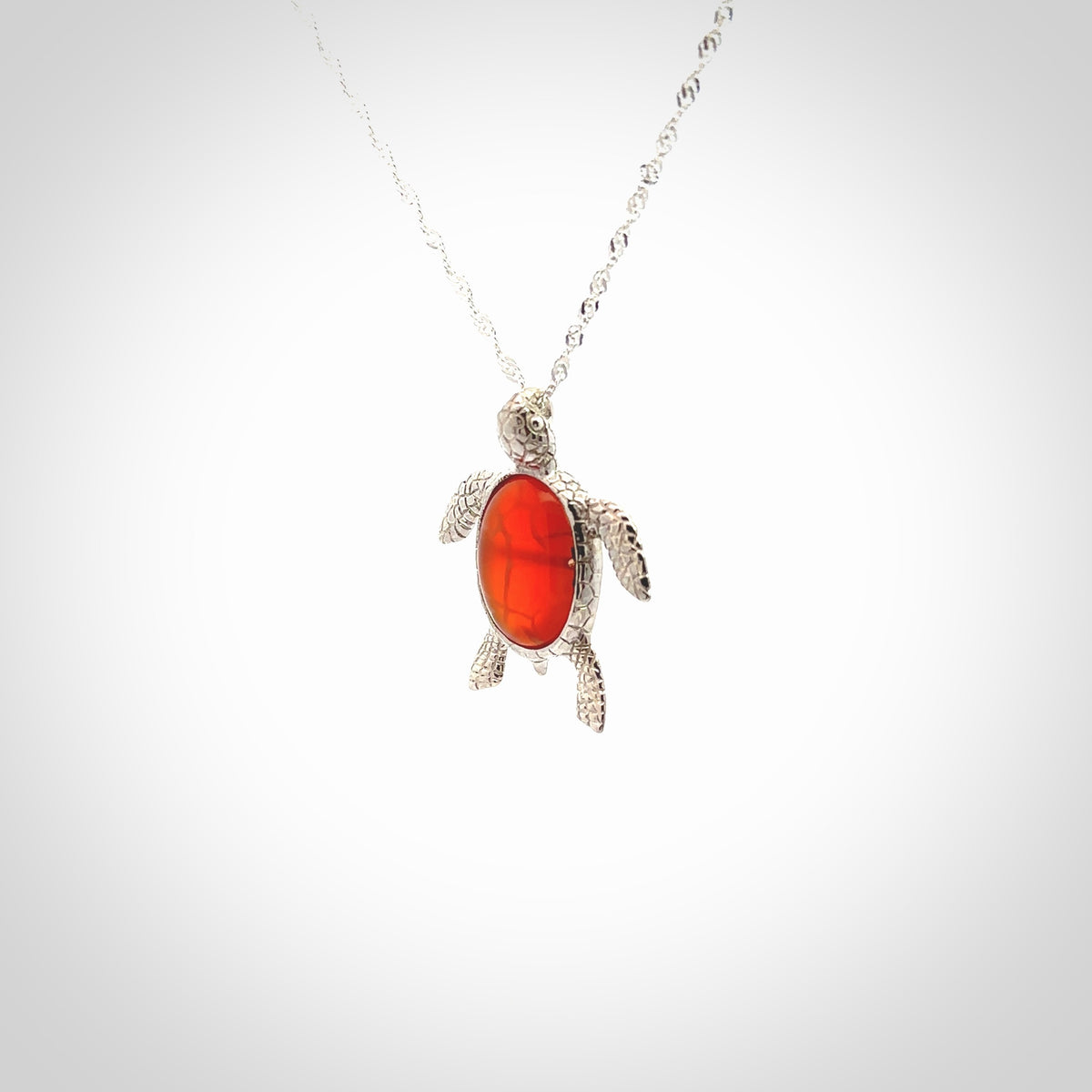 Fire Agate stone turtle in Sterling silver engraved casing. Hand carved jewellery made by NZ Pacific and for sale online. Moana, Ocean, jewellery hand carved in fire agate and Sterling Silver turtle necklace.