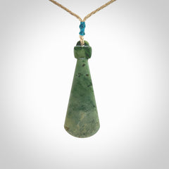 This is a sleek and slender hand carved New Zealand Jade mere pendant. The stone is a light green with mottled inclusions. The cord is tan and adjustable. The pendant has a light polish and just glows. Delivered in a woven kete pouch.