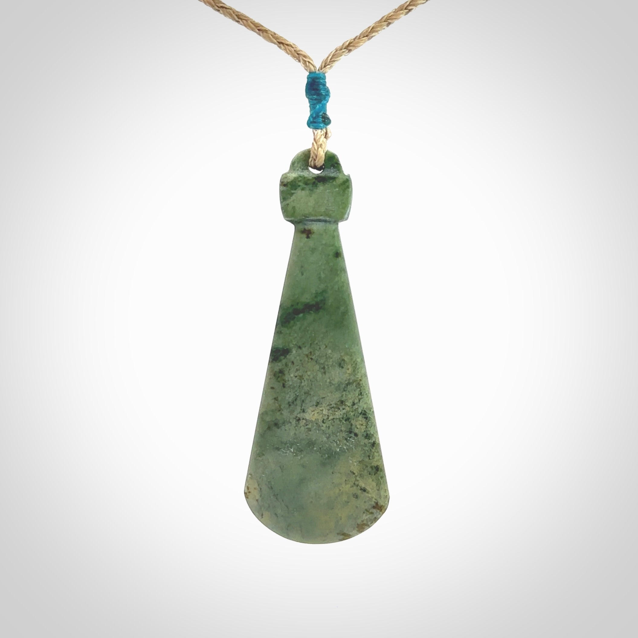 This is a sleek and slender hand carved New Zealand Jade mere pendant. The stone is a light green with mottled inclusions. The cord is tan and adjustable. The pendant has a light polish and just glows. Delivered in a woven kete pouch.