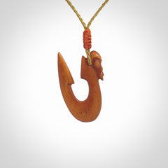 Natural stained cow bone manaia with hook pendant. Hand carved by Yuri Terenyi in New Zealand. Unique design pendant for sale online. One only stained bone manaia, hook necklace. Free delivery worldwide. Delivered with an adjustable cord.