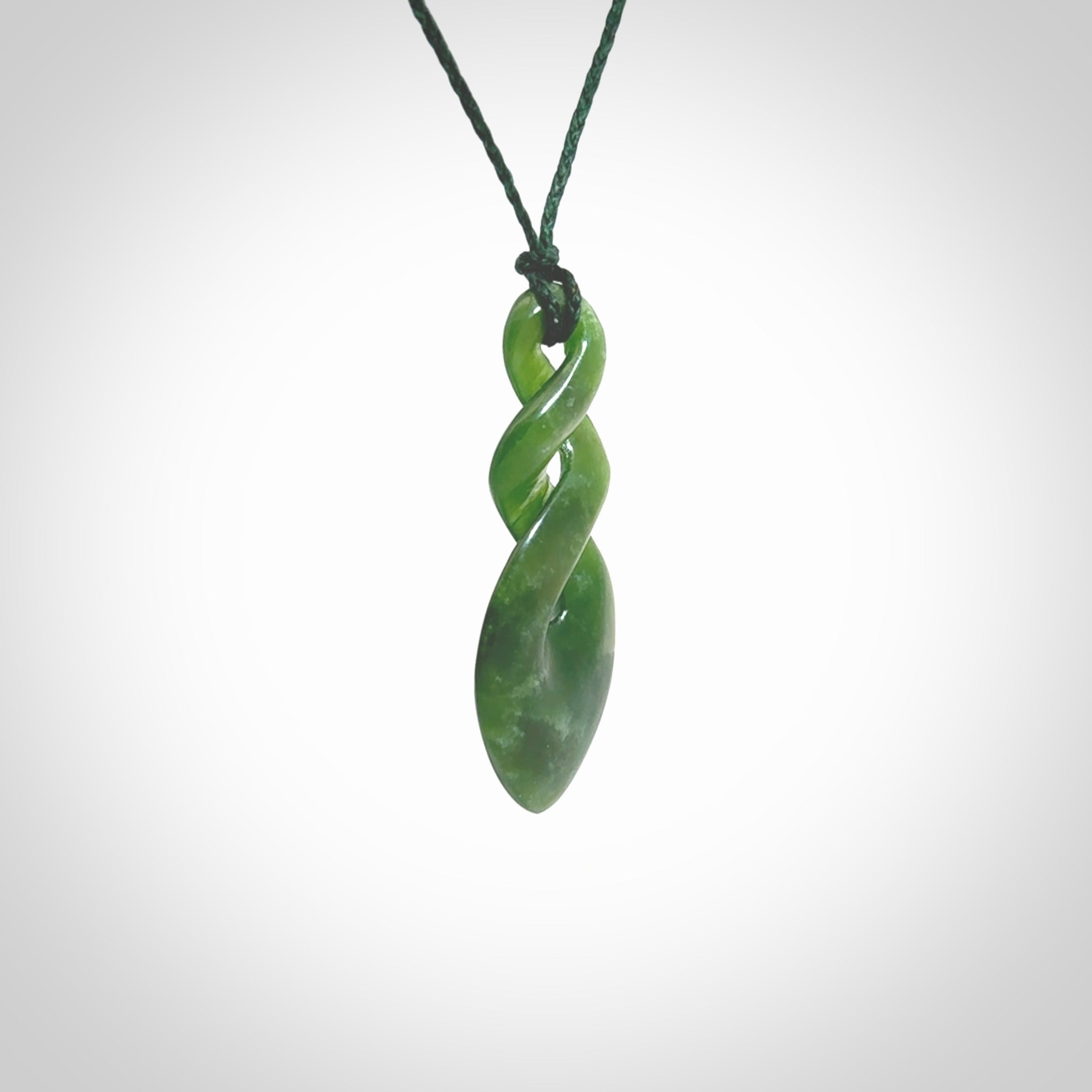 Hand carved New Zealand jade twist pendant. Carved in New Zealand by NZ Pacific. Unique double twist jewellery for sale online. Provided with an adjustable Manuka Green cord.