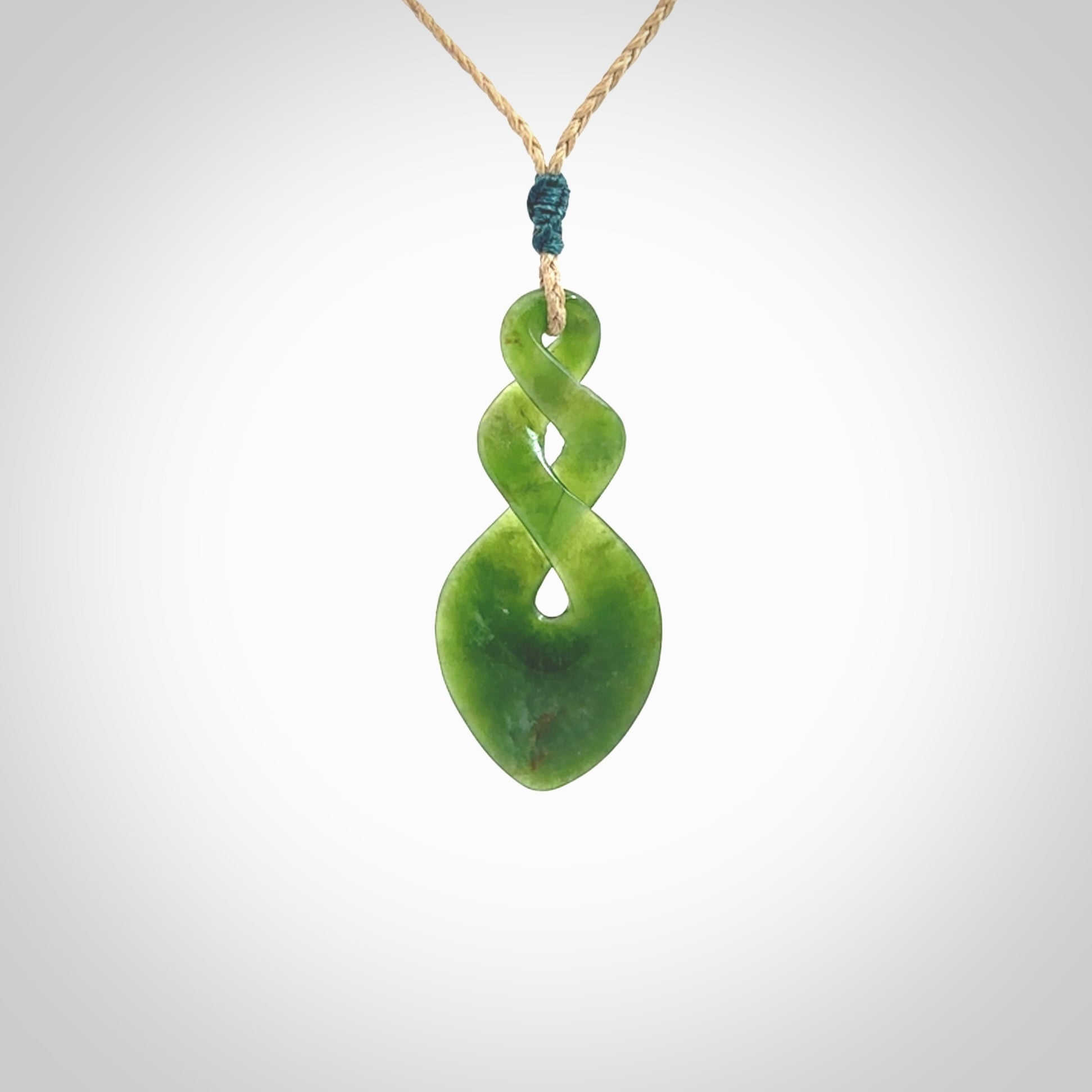 Hand carved New Zealand jade twist pendant. Carved in New Zealand by NZ Pacific. Unique double twist jewellery for sale online. Provided with an adjustable tan cord.