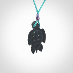 This picture shows a hand carved black jade turtle pendant. It is polished to a soft shine and has quite a lot of detail carved into the jade. The cord is a hand plaited Paradise Blue, waxed polyester. Carved by NZ Pacific.