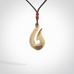 A fish hook necklace (hei-matau) hand-carved in a traditional style from Woolly Mammoth Tusk. These are glorious pieces of art to wear. Provided with adjustable cords and packaged in a woven kete pouch. Delivered with express courier.