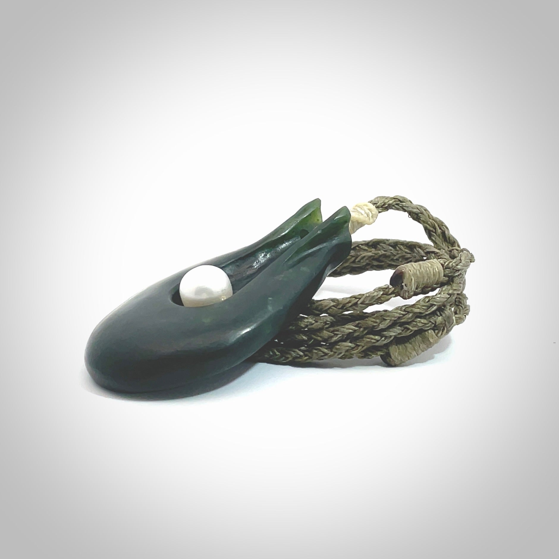 This is a unique contemporary drop pendant, hand carved from New Zealand Jade with Pearl insert. The cord is olive green and is length adjustable. This is delivered to you with Express Courier. Hand carved Pounamu, Jade necklace with adjustable cord from Ana Krakosky.