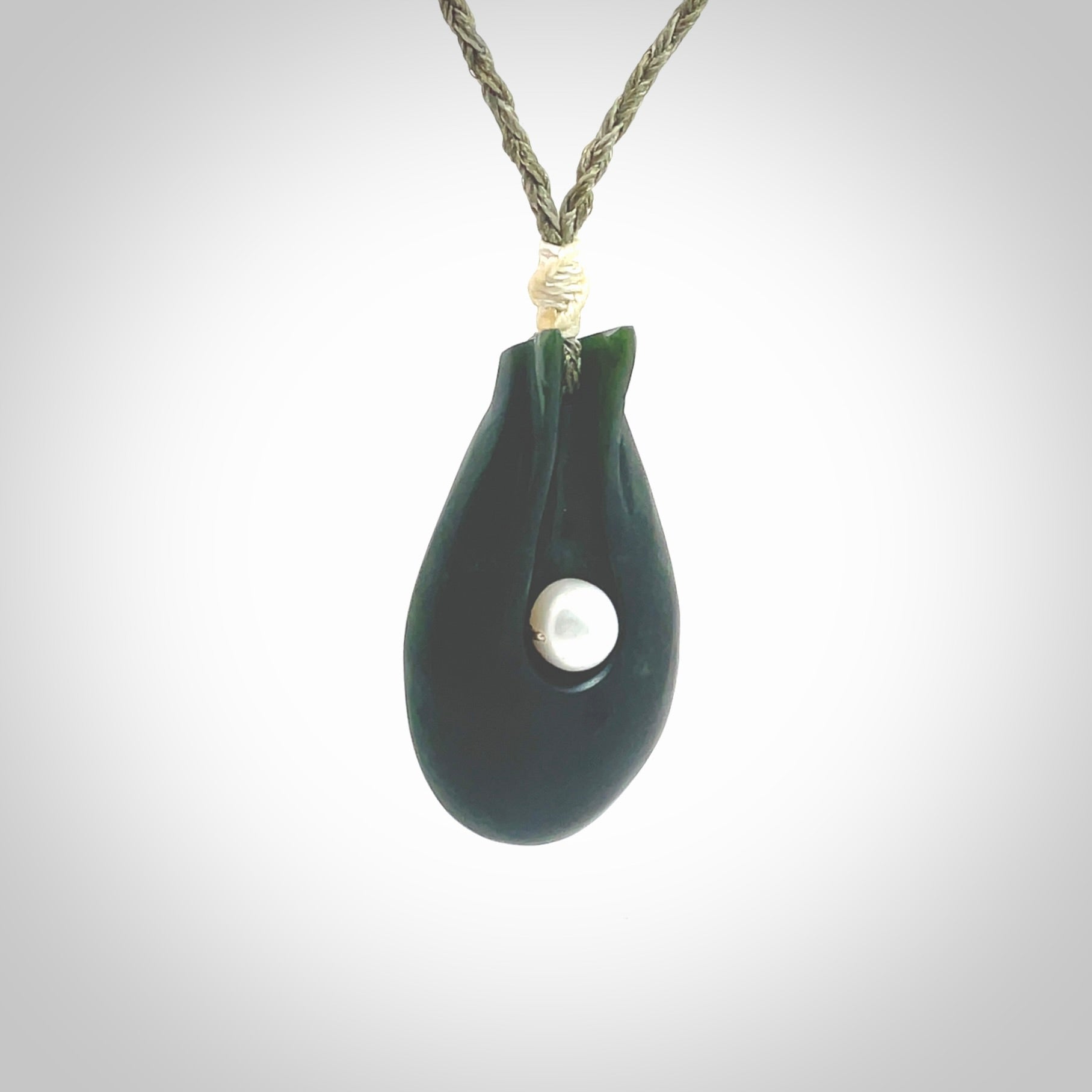 This is a unique contemporary drop pendant, hand carved from New Zealand Jade with Pearl insert. The cord is olive green and is length adjustable. This is delivered to you with Express Courier. Hand carved Pounamu, Jade necklace with adjustable cord from Ana Krakosky.