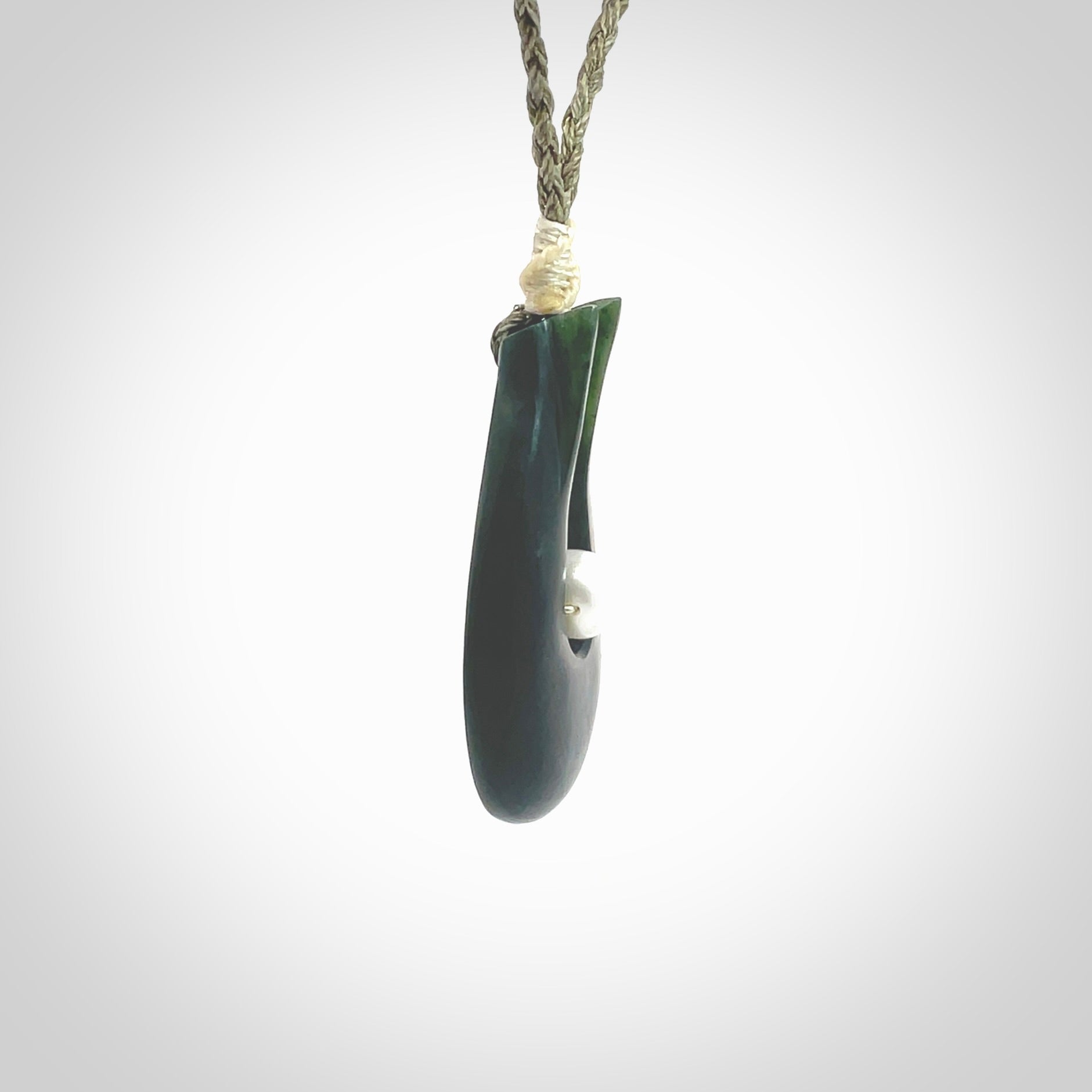 This is a unique contemporary drop pendant, hand carved from New Zealand Jade with Pearl insert. The cord is olive green and is length adjustable. This is delivered to you with Express Courier. Hand carved Pounamu, Jade necklace with adjustable cord from Ana Krakosky.