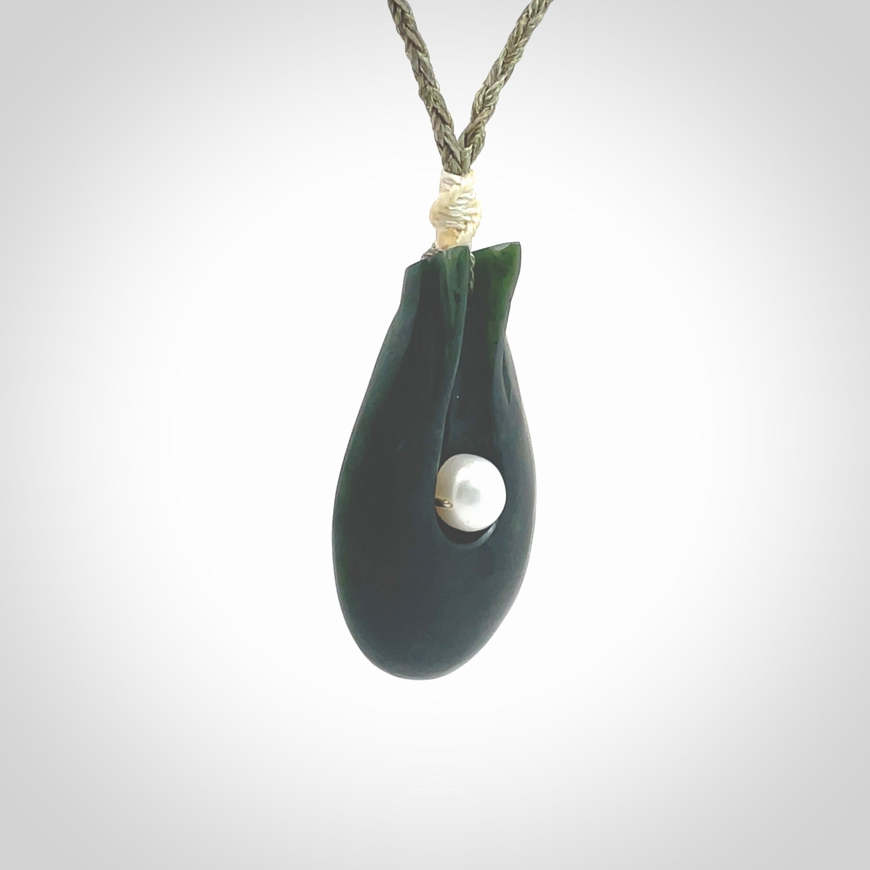 This is a unique contemporary drop pendant, hand carved from New Zealand Jade with Pearl insert. The cord is olive green and is length adjustable. This is delivered to you with Express Courier. Hand carved Pounamu, Jade necklace with adjustable cord from Ana Krakosky.