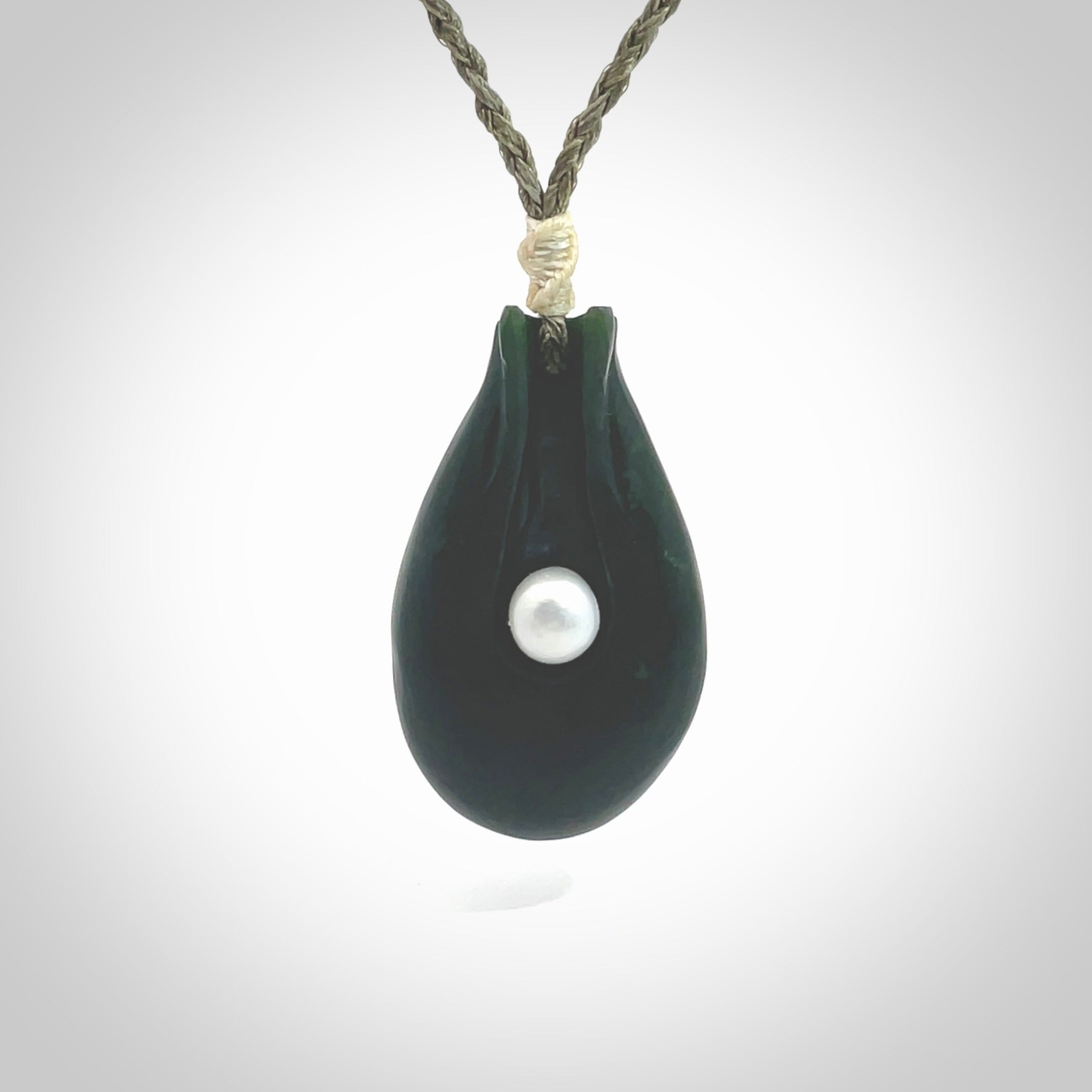 This is a unique contemporary drop pendant, hand carved from New Zealand Jade with Pearl insert. The cord is olive green and is length adjustable. This is delivered to you with Express Courier. Hand carved Pounamu, Jade necklace with adjustable cord from Ana Krakosky.