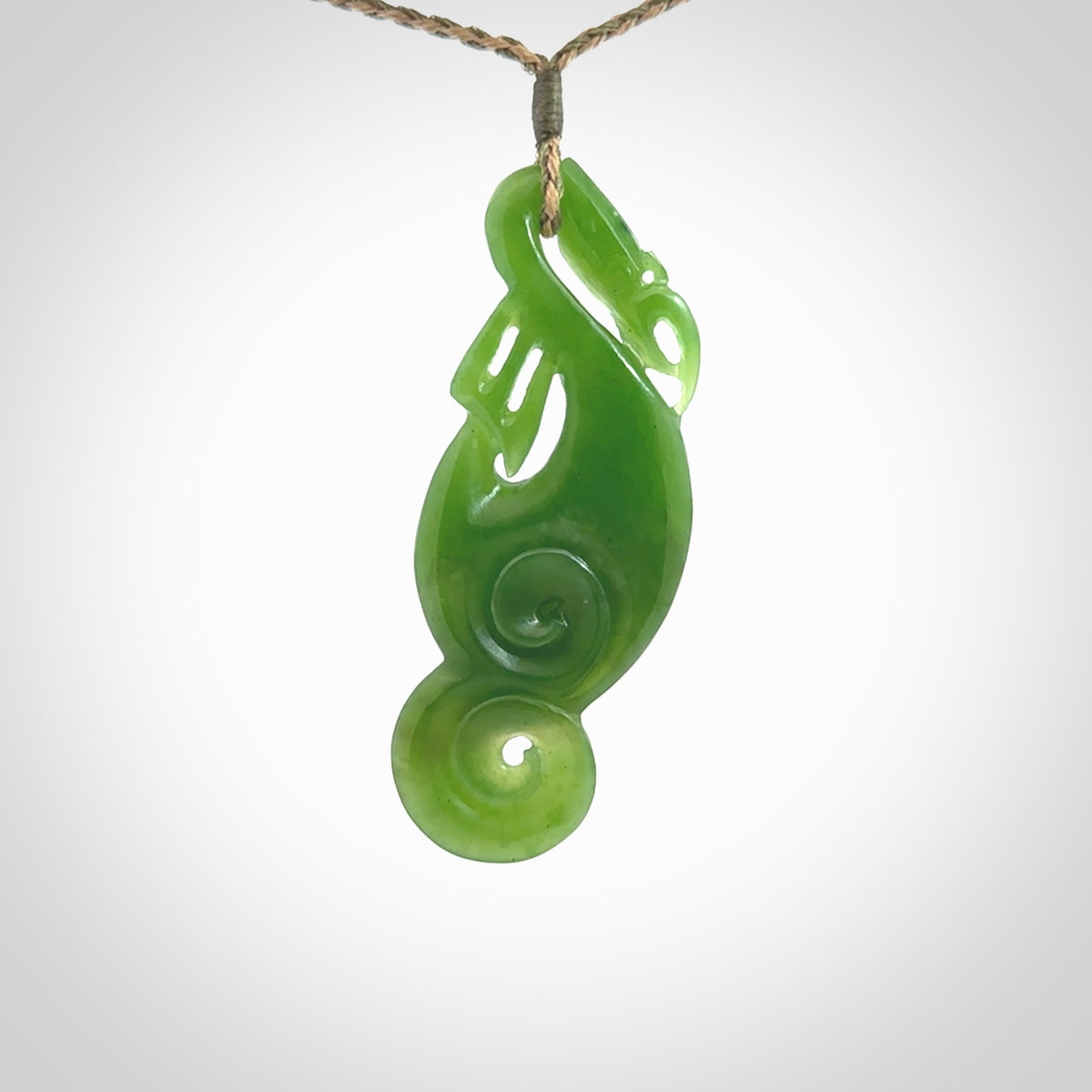 This pendant is a beautiful large New Zealand Auhunga green jade manaia pendant with koru. It has the head of a bird and the tail of a fish and also two koru carved into the body. It is carved by Ross Crump here in New Zealand. Provided with an adjustable tan/khaki cord.