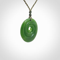 This picture shows a detailed koru carving. A pendant carved from a lovely piece of New Zealand jade, Pounamu. We have suspended this necklace on a hand plaited cord in Khaki and you can adjust its length so that you can position the pendant where it suits you best.