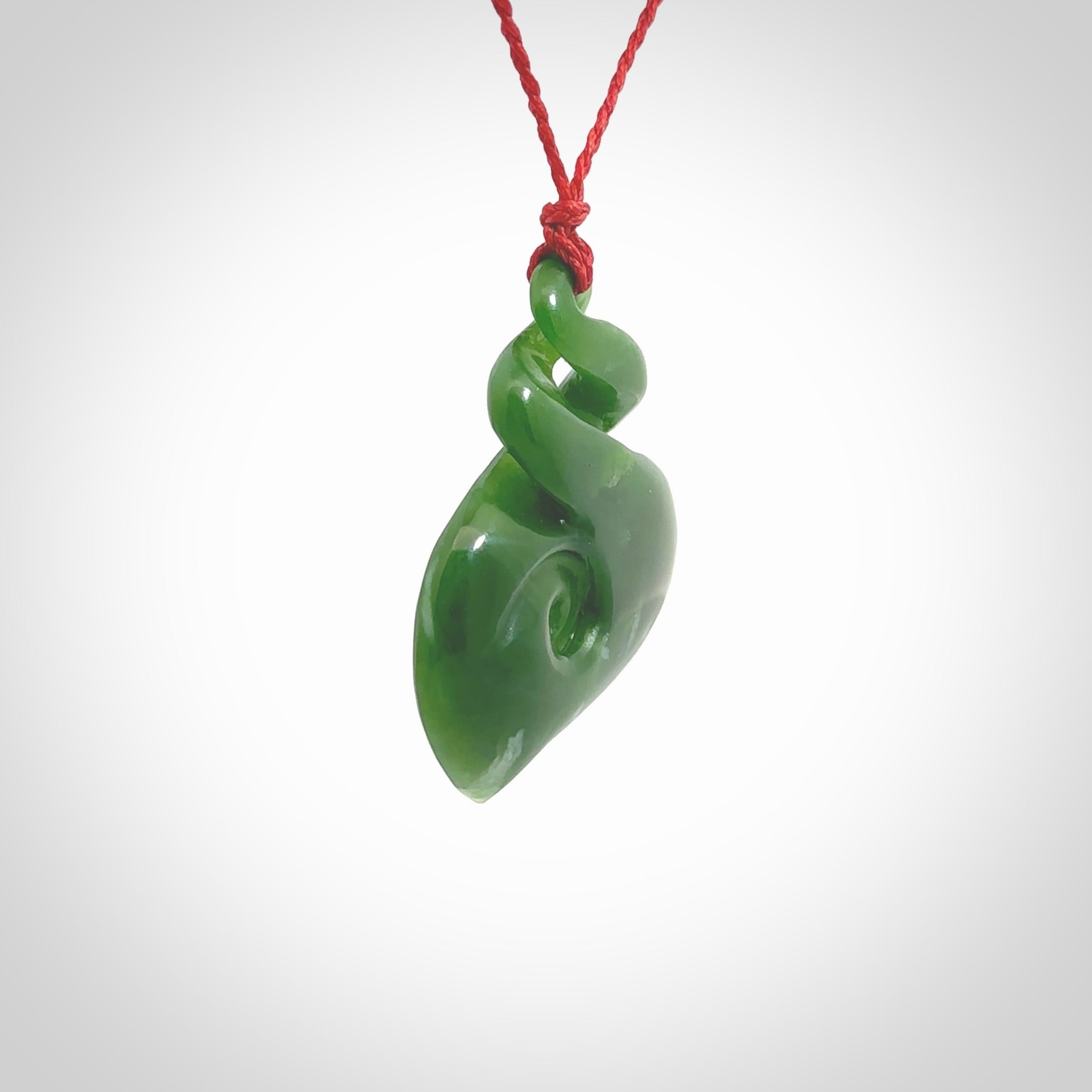 A beautiful carved double twist with koru pendant. This piece has been carved for us by Ross Crump and is a truly beautiful carving made from some of our finest and rarest jade. We will ship this to you with an express courier so you will have it quickly. A rare and beautiful work of wearable art from NZ Pacific.