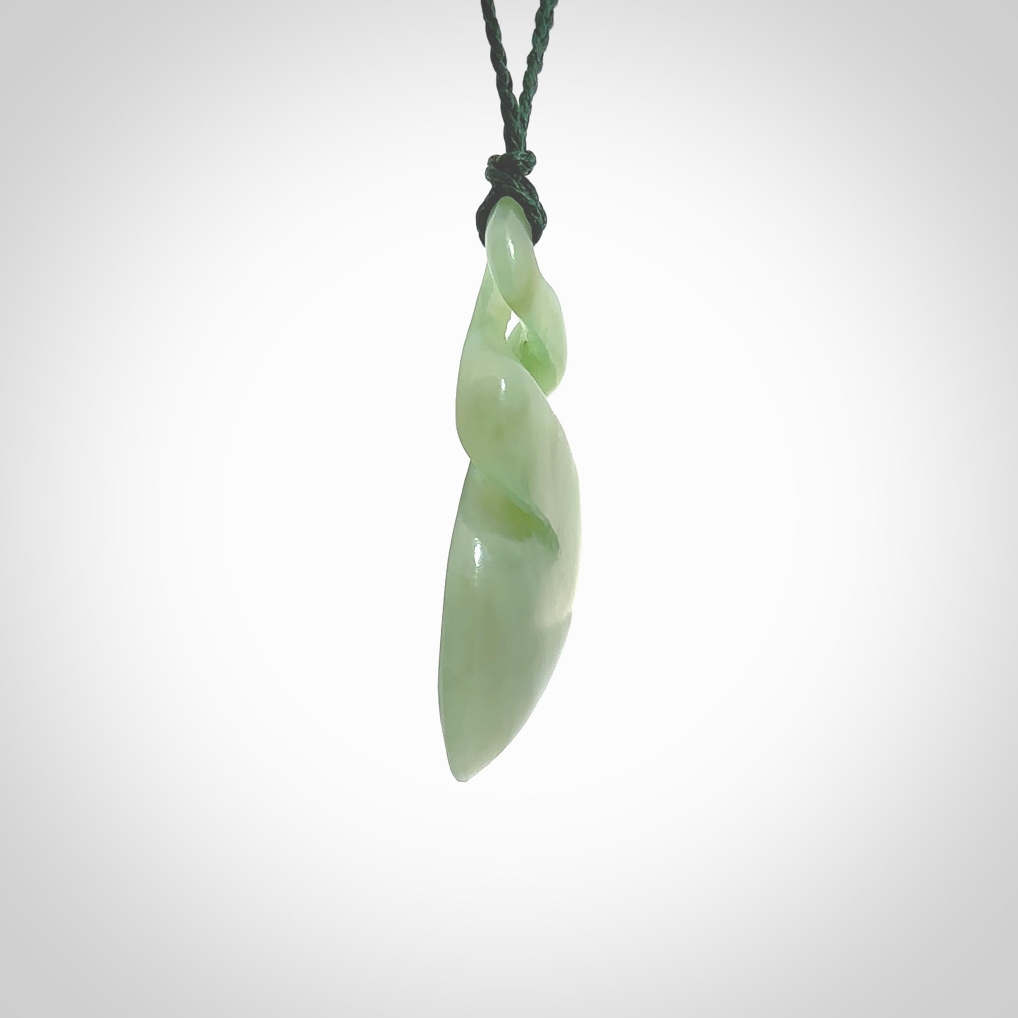 This piece is a fine, delicate drop shaped, double twist pendant. It was carved for us by Ross Crump from a lovely bright semi-translucent green piece of New Zealand Inanga jade. It is suspended on an manuka green coloured braided cord that is length adjustable.