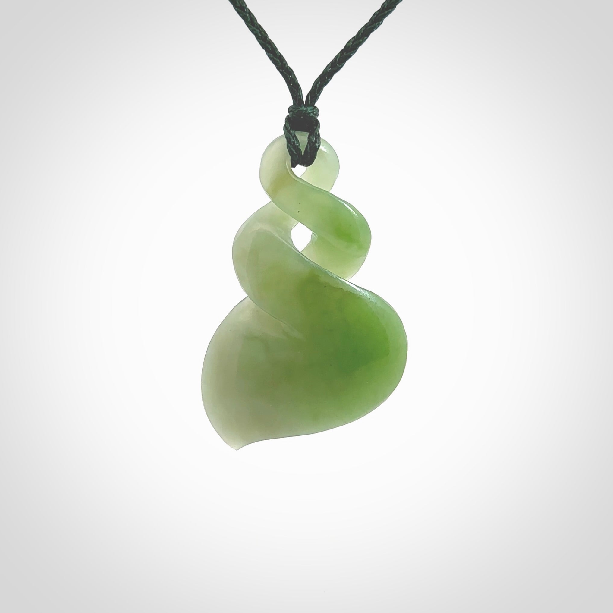 This piece is a fine, delicate drop shaped, double twist pendant. It was carved for us by Ross Crump from a lovely bright semi-translucent green piece of New Zealand Inanga jade. It is suspended on an manuka green coloured braided cord that is length adjustable.