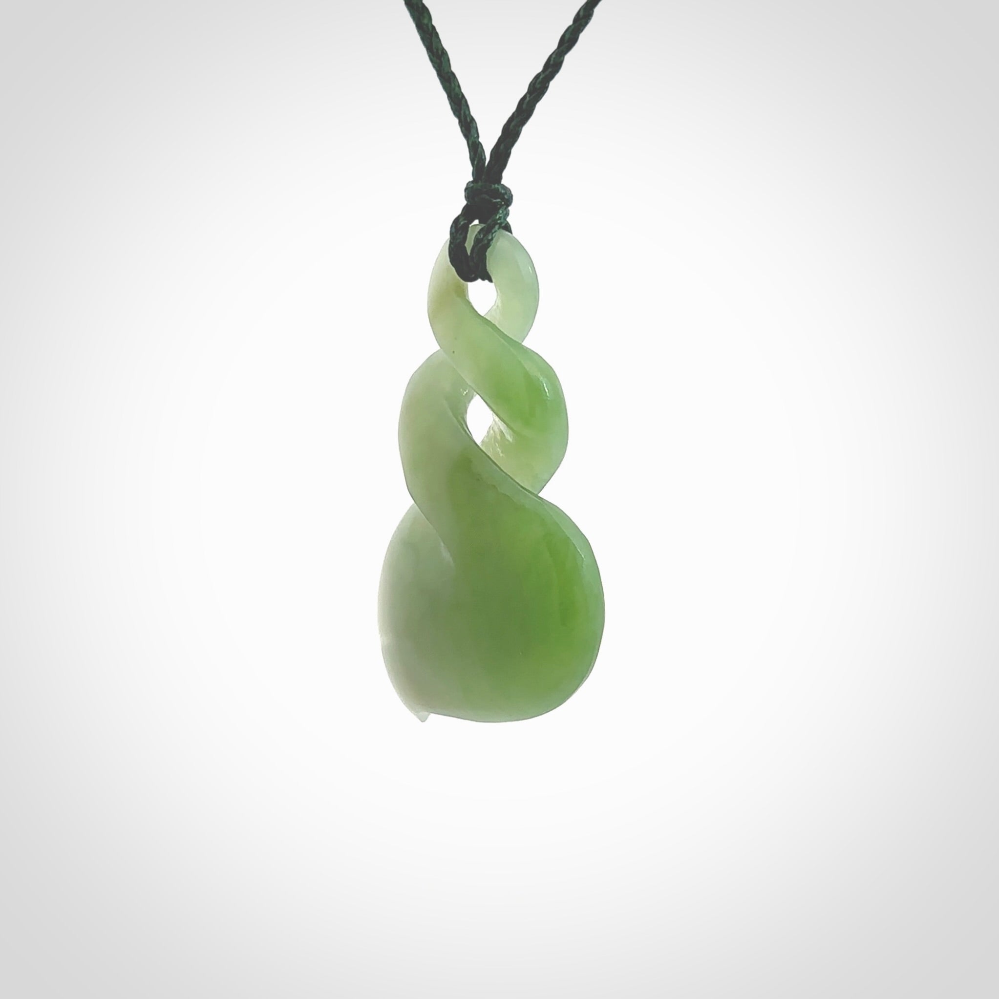 This piece is a fine, delicate drop shaped, double twist pendant. It was carved for us by Ross Crump from a lovely bright semi-translucent green piece of New Zealand Inanga jade. It is suspended on an manuka green coloured braided cord that is length adjustable.