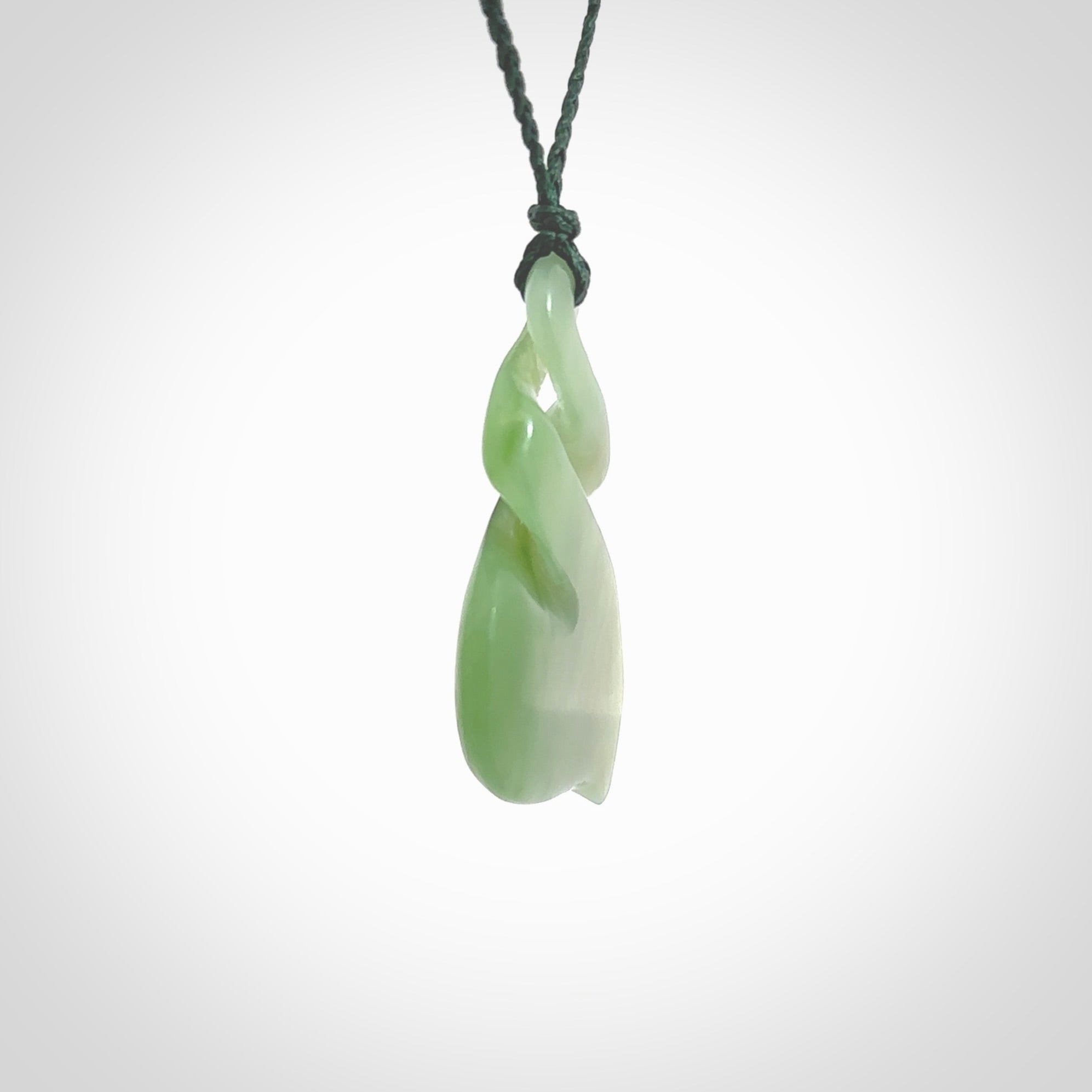 This piece is a fine, delicate drop shaped, double twist pendant. It was carved for us by Ross Crump from a lovely bright semi-translucent green piece of New Zealand Inanga jade. It is suspended on an manuka green coloured braided cord that is length adjustable.