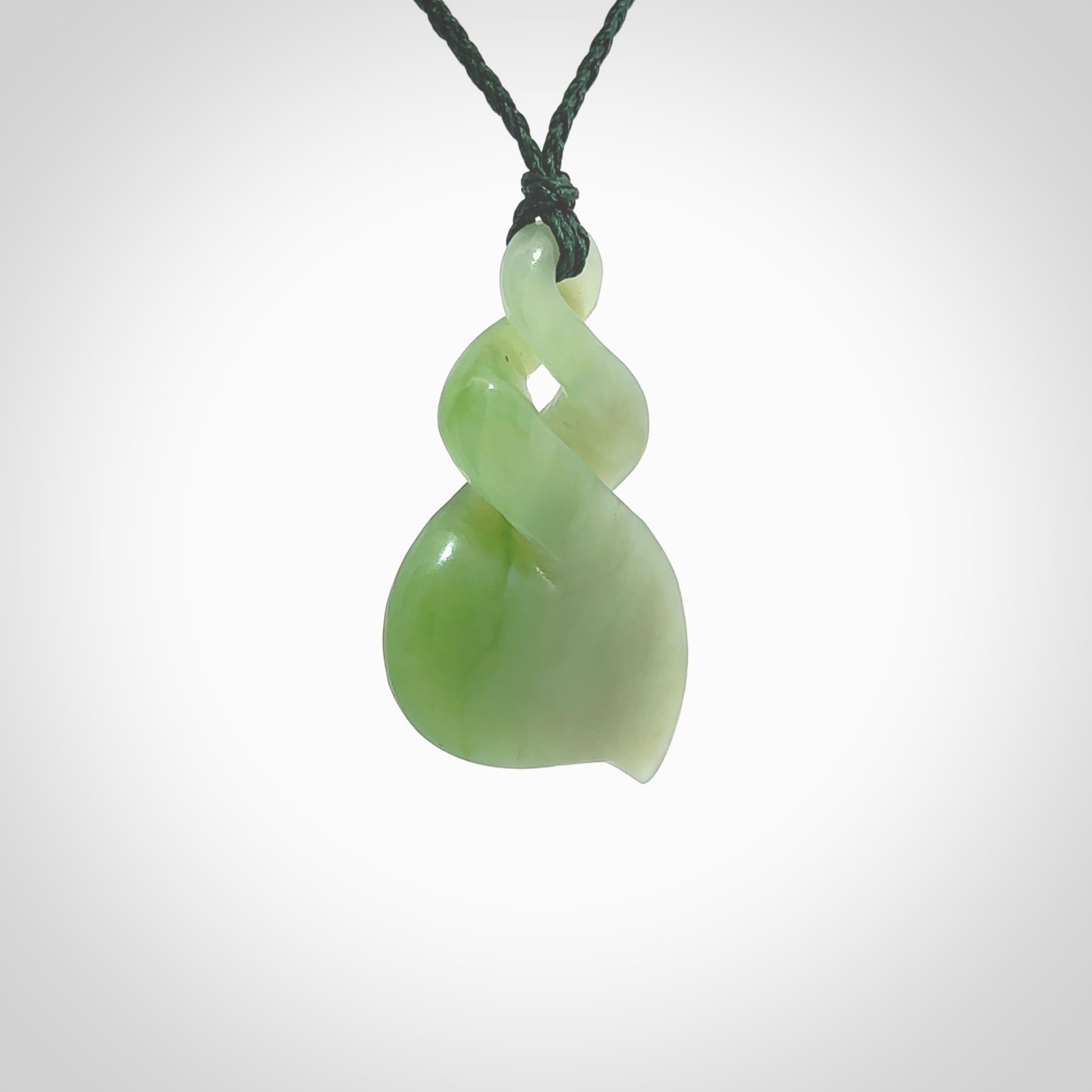 This piece is a fine, delicate drop shaped, double twist pendant. It was carved for us by Ross Crump from a lovely bright semi-translucent green piece of New Zealand Inanga jade. It is suspended on an manuka green coloured braided cord that is length adjustable.