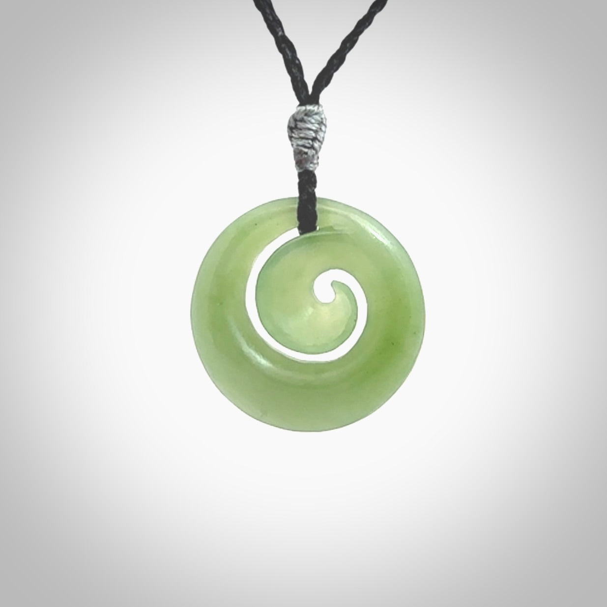 This picture shows a koru carving. A pendant carved from a lovely piece of New Zealand Inanga jade. We have suspended this necklace on a hand plaited cord in black and you can adjust its length so that you can position the pendant where it suits you best.