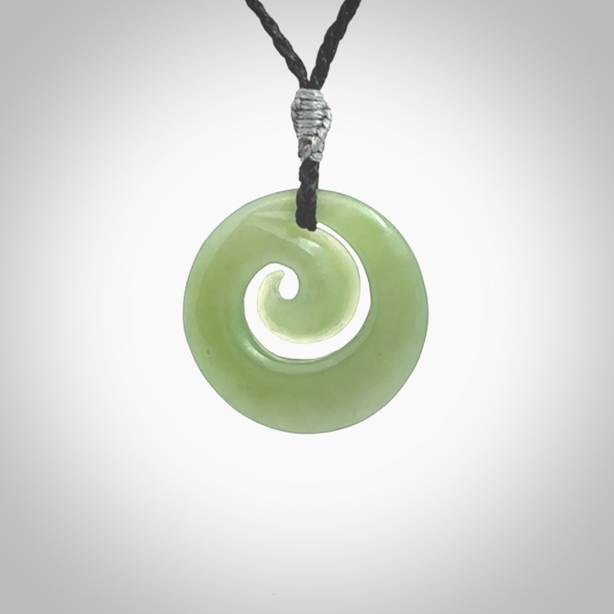 This picture shows a koru carving. A pendant carved from a lovely piece of New Zealand Inanga jade. We have suspended this necklace on a hand plaited cord in black and you can adjust its length so that you can position the pendant where it suits you best.