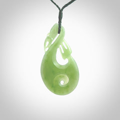 Hand carved New Zealand Inanga jade manaia with koru pendant. Carved from beautiful New Zealand Jade for NZ Pacific by Ross Crump. Unique jade jewellery for sale online. Provided with an adjustable manuka green cord.