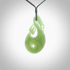 Hand carved New Zealand Inanga jade manaia with koru pendant. Carved from beautiful New Zealand Jade for NZ Pacific by Ross Crump. Unique jade jewellery for sale online. Provided with an adjustable manuka green cord.