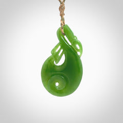 Hand carved New Zealand Kahurangi jade manaia with koru pendant. Carved from beautiful New Zealand Jade for NZ Pacific by Ross Crump. Unique jade jewellery for sale online. Provided with an adjustable tan/khaki cord.