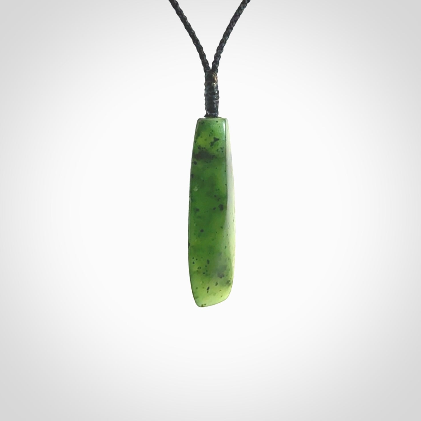 A lovely medium sized New Zealand Kawakawa jade drop pendant. This piece is made from a semi-translucent green jade with black specks and is a wonderful colour. Carved by Ric Moor for NZ Pacific and delivered worldwide. Provided with an adjustable black cord.