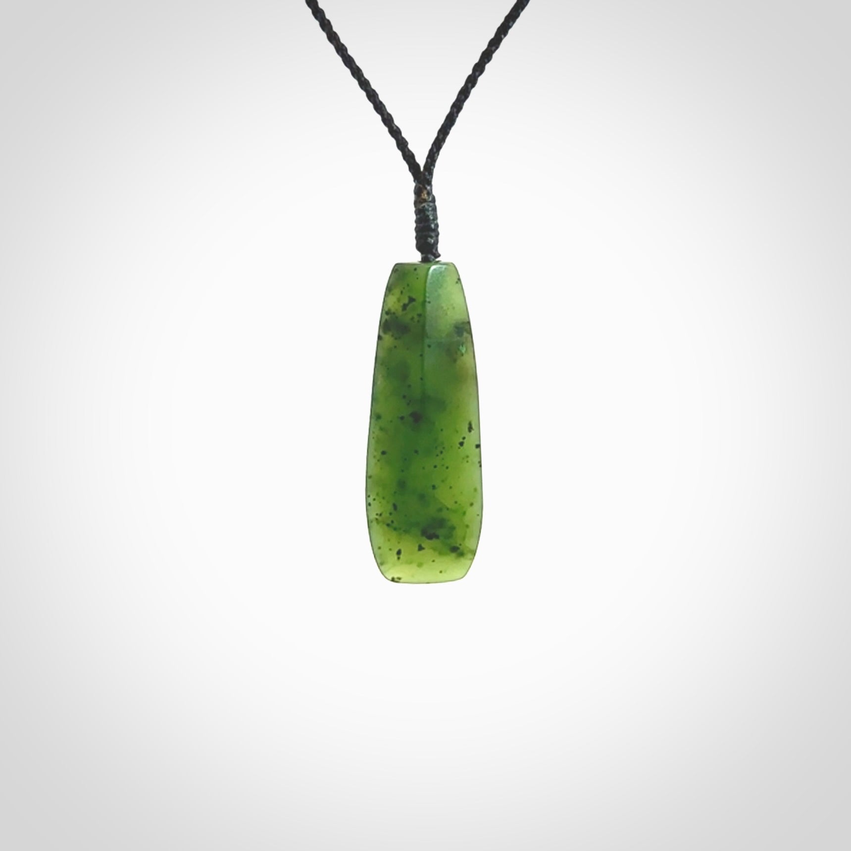 A lovely medium sized New Zealand Kawakawa jade drop pendant. This piece is made from a semi-translucent green jade with black specks and is a wonderful colour. Carved by Ric Moor for NZ Pacific and delivered worldwide. Provided with an adjustable black cord.