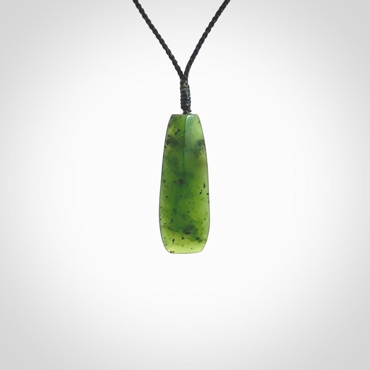 A lovely medium sized New Zealand Kawakawa jade drop pendant. This piece is made from a semi-translucent green jade with black specks and is a wonderful colour. Carved by Ric Moor for NZ Pacific and delivered worldwide. Provided with an adjustable black cord.