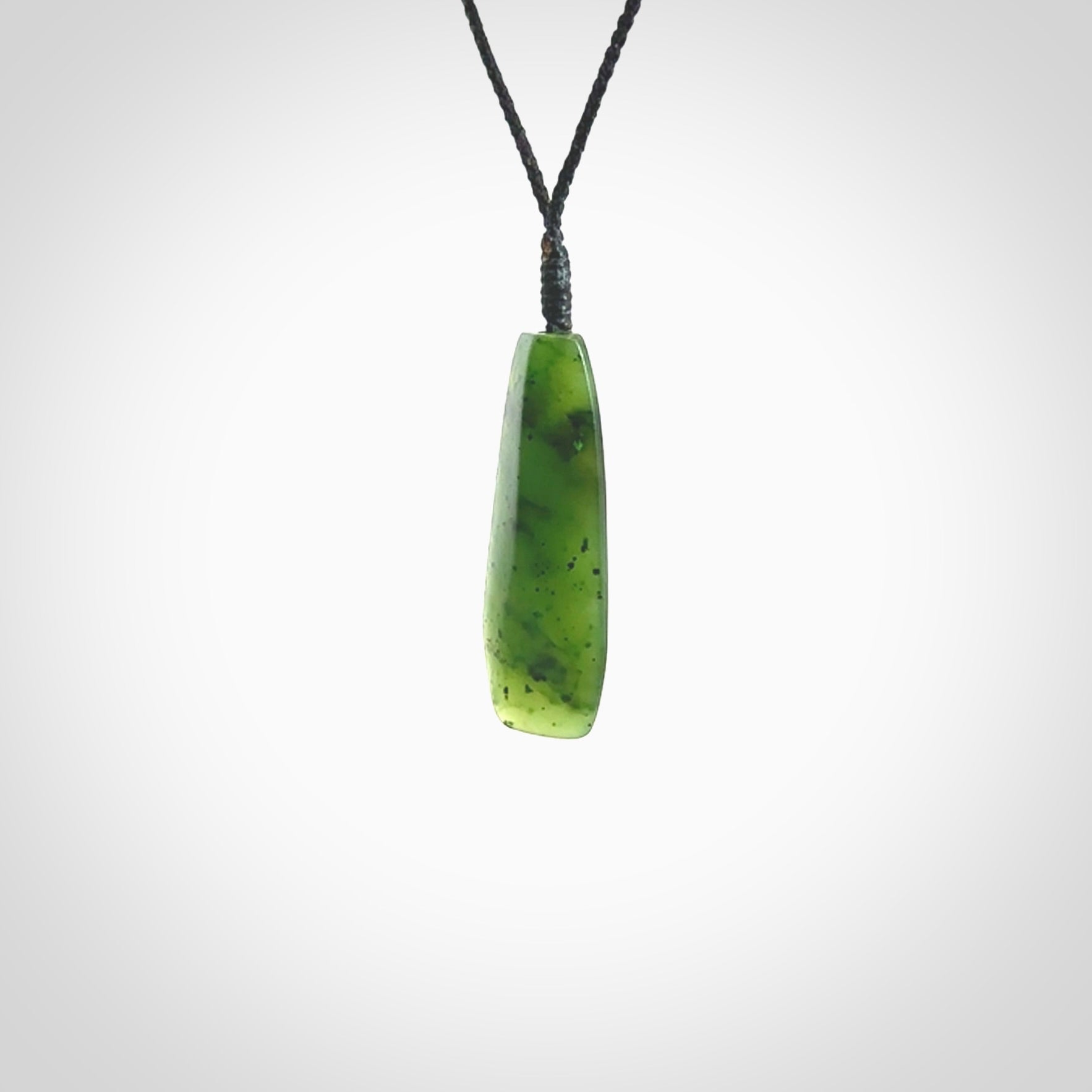 A lovely medium sized New Zealand Kawakawa jade drop pendant. This piece is made from a semi-translucent green jade with black specks and is a wonderful colour. Carved by Ric Moor for NZ Pacific and delivered worldwide. Provided with an adjustable black cord.