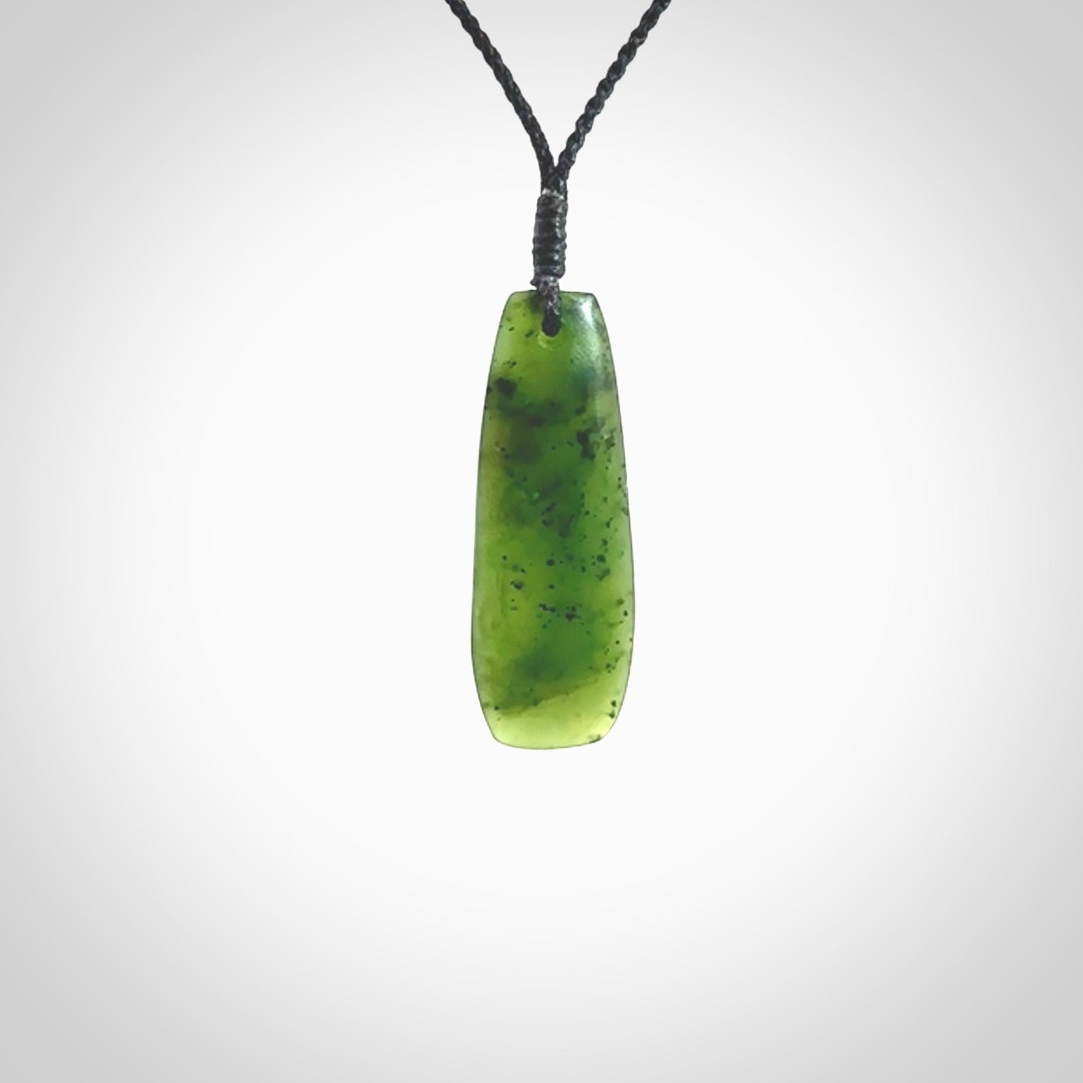 A lovely medium sized New Zealand Kawakawa jade drop pendant. This piece is made from a semi-translucent green jade with black specks and is a wonderful colour. Carved by Ric Moor for NZ Pacific and delivered worldwide. Provided with an adjustable black cord.