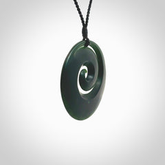 This is a large deep and dark green New Zealand jade koru pendant. We have bound this with a black coloured cord necklace. The necklace is adjustable so you can position the piece where it suits you the best. Hand made by Ric Moor.