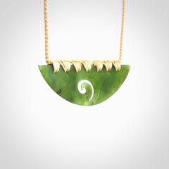 This picture shows a hand carved jade half-shield with Koru pendant. It is a semi-translucent green colour. This is a wonderful piece of jewellery. The cord is hand plaited and adjustable so that you can position the pendant where it suits you best. This piece was carved for us by Ric Moor. Delivery is free worldwide.