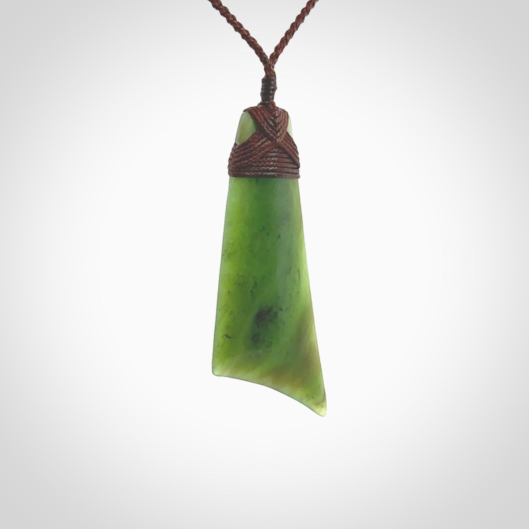 Hand carved Toki pendant from a lovely piece of local New Zealand Totoweka Jade. The quality of the workmanship and design is outstanding - this is a piece you will want to wear all the time. We have suspended this from a 4-plait brown cord which can be adjusted with a couple of slip knots and brown binding.