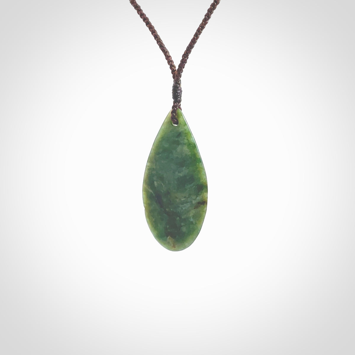 This photo shows a medium sized New Zealand jade drop shaped pendant. It a a lovely deep green jade. The cord is a four plait brown and is adjustable in length. One only medium, contemporary drop necklace from Jade, by Ric Moor.