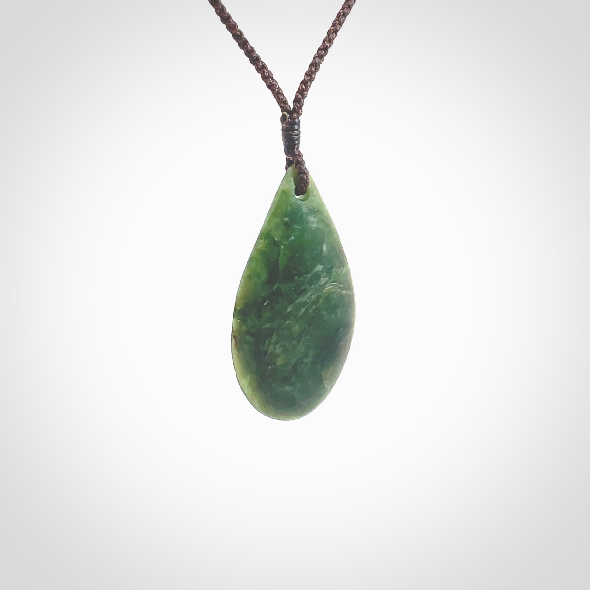 This photo shows a medium sized New Zealand jade drop shaped pendant. It a a lovely deep green jade. The cord is a four plait brown and is adjustable in length. One only medium, contemporary drop necklace from Jade, by Ric Moor.