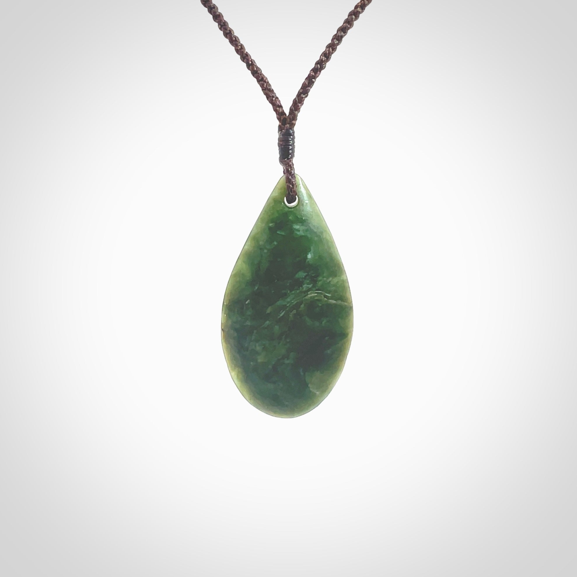 This photo shows a medium sized New Zealand jade drop shaped pendant. It a a lovely deep green jade. The cord is a four plait brown and is adjustable in length. One only medium, contemporary drop necklace from Jade, by Ric Moor.