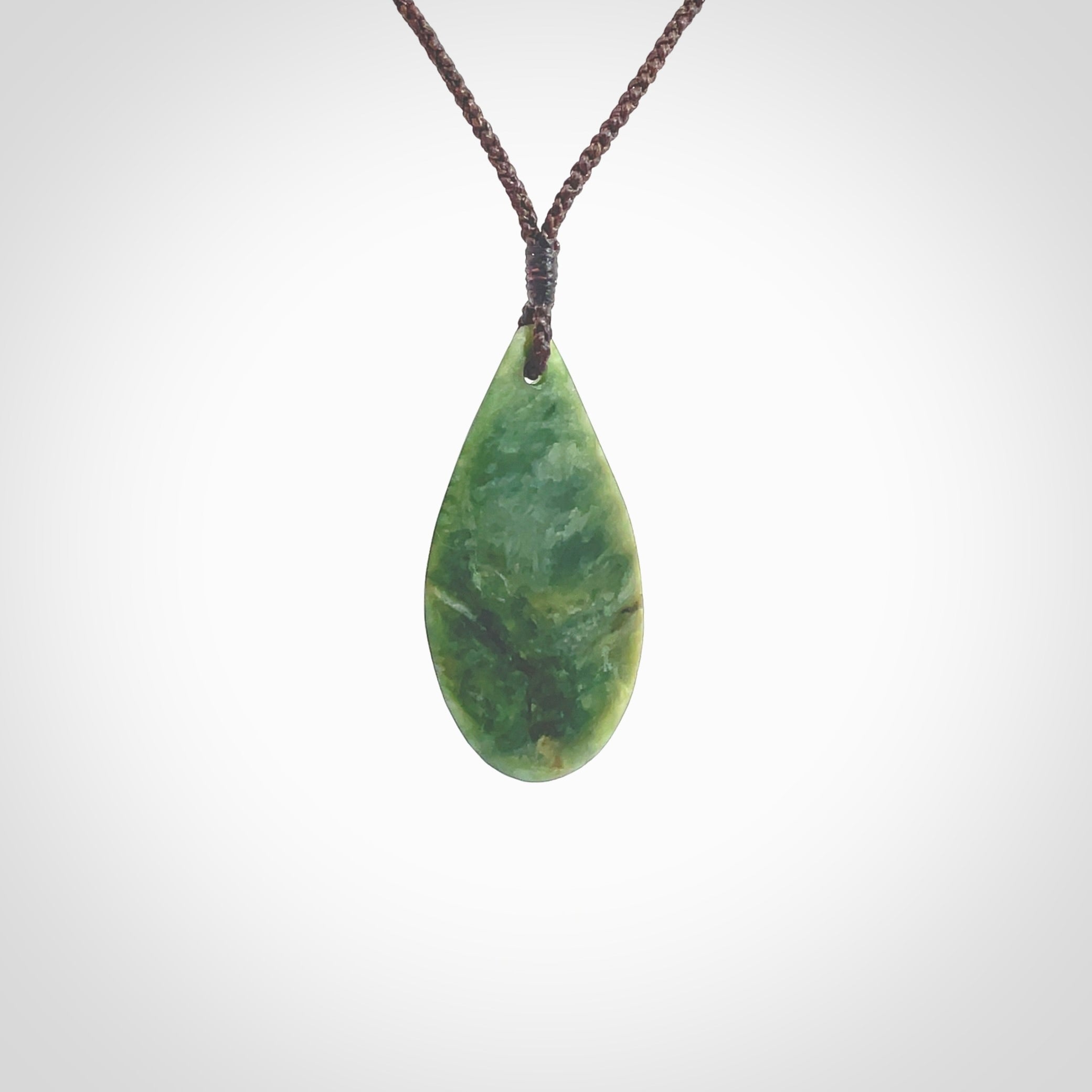 This photo shows a medium sized New Zealand jade drop shaped pendant. It a a lovely deep green jade. The cord is a four plait brown and is adjustable in length. One only medium, contemporary drop necklace from Jade, by Ric Moor.