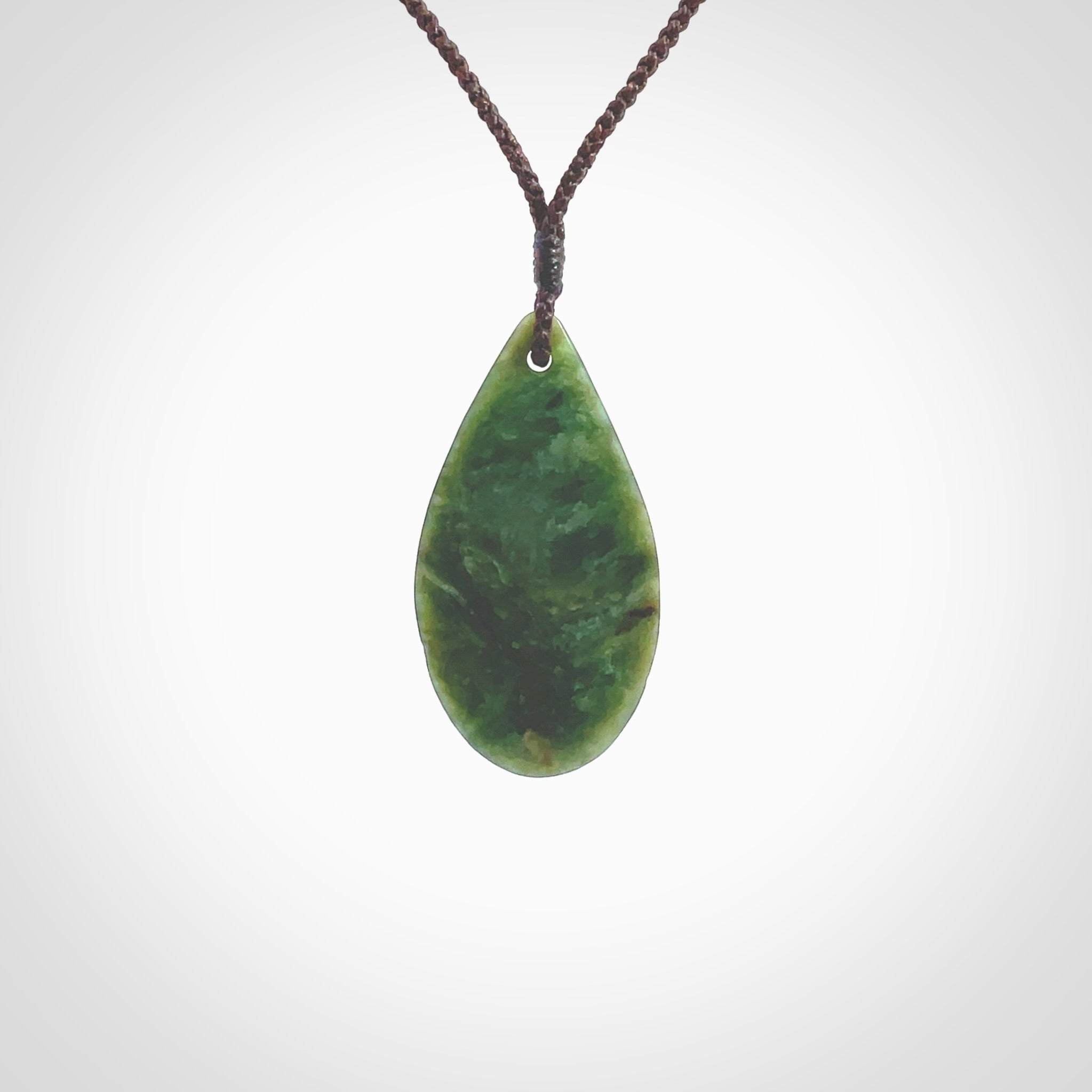 This photo shows a medium sized New Zealand jade drop shaped pendant. It a a lovely deep green jade. The cord is a four plait brown and is adjustable in length. One only medium, contemporary drop necklace from Jade, by Ric Moor.