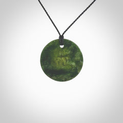 A lovely disc design with cupping on one side and the lightly convex form on the other - a little feature that captures the light and gives the piece a sense of movement and form. Hand made from New Zealand Jade by Ric Moor. Delivered with an adjustable black cord.&nbsp;