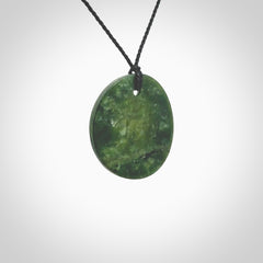 A lovely disc design with cupping on one side and the lightly convex form on the other - a little feature that captures the light and gives the piece a sense of movement and form. Hand made from New Zealand Jade by Ric Moor. Delivered with an adjustable black cord.&nbsp;