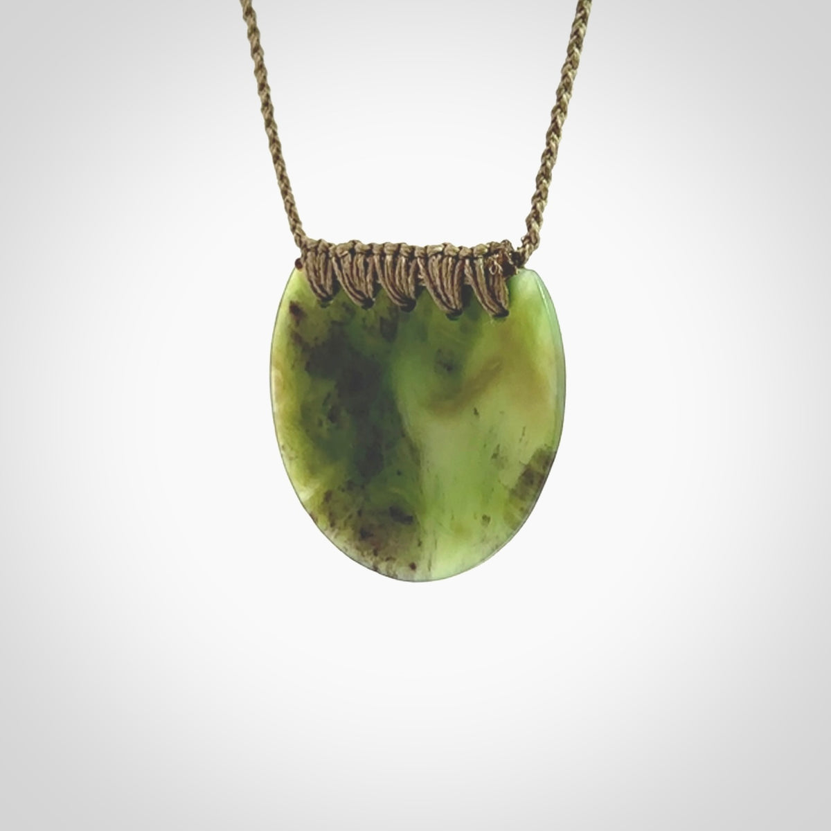 This piece is a disc pendant, hand carved for us by Ric Moor from a lovely milky green piece of New Zealand jade. It is suspended on a olive coloured braided cord that is length adjustable.